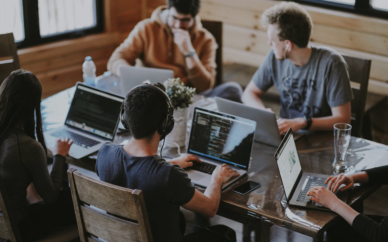 A team working on laptops together around a long table.
